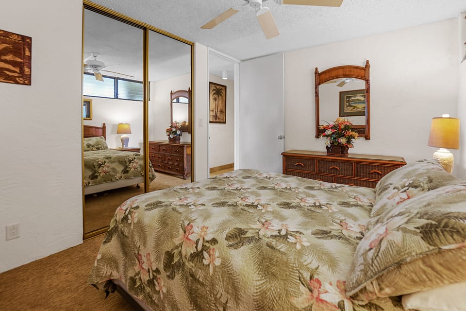 A calming bedroom with floral bedding, wicker furniture, and soft lighting. Ideal for a peaceful retreat with subtle tropical accents.