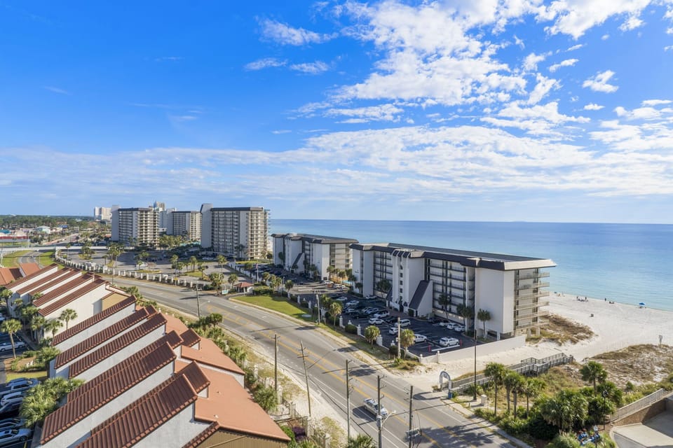 View of beachfront condominiums along the coast with clear skies and ocean in the background