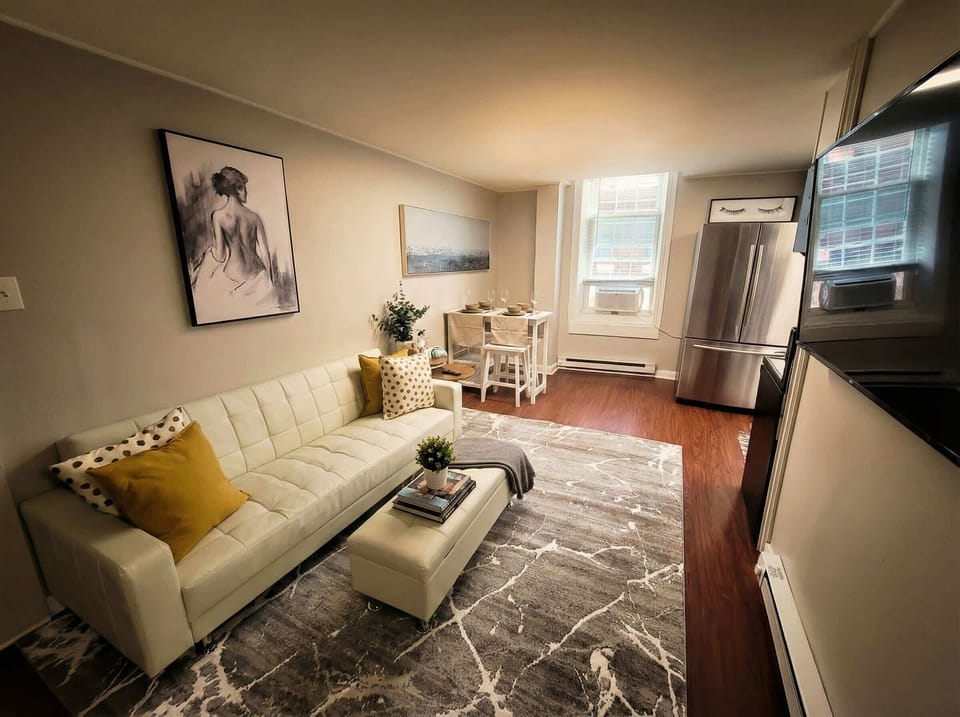Living area with sofa, coffee table, dining nook, refrigerator, and TV.