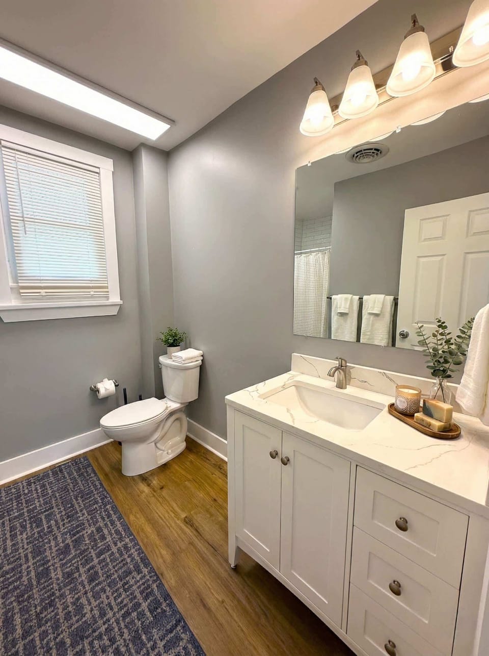 Bathroom vanity area with mirror, sink, toilet, and fresh towels.