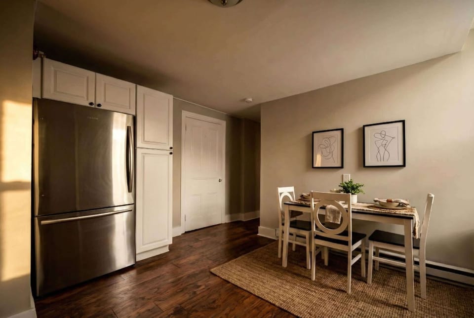 Dining nook beside the kitchen with table seating, stainless steel refrigerator, and white cabinetry.