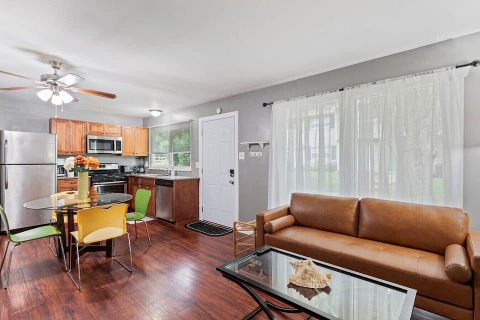 Cute kitchen , a brand new washer ,dryer, colorful furniture like a table, big windows that let in natural light, a comfy genuine sofa, and a ceiling fan for added comfort ,all of these components contribute to creating a cozy living space