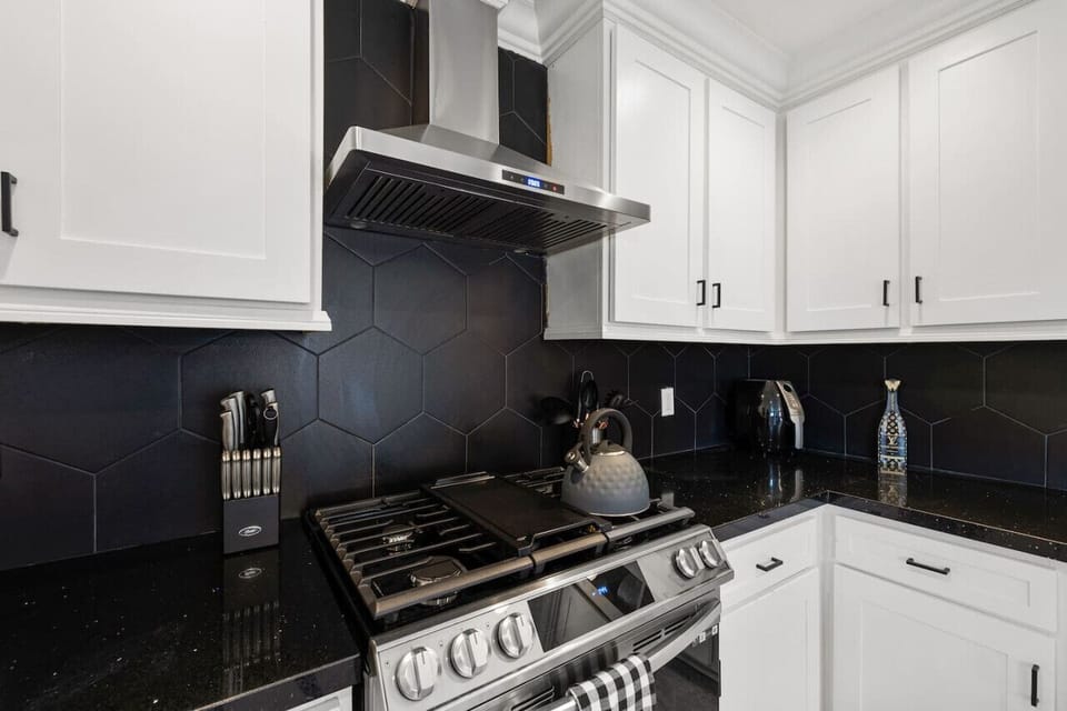 Sleek kitchen w/ glossy backsplash, modern appliances & everything set up for easy home cooking.