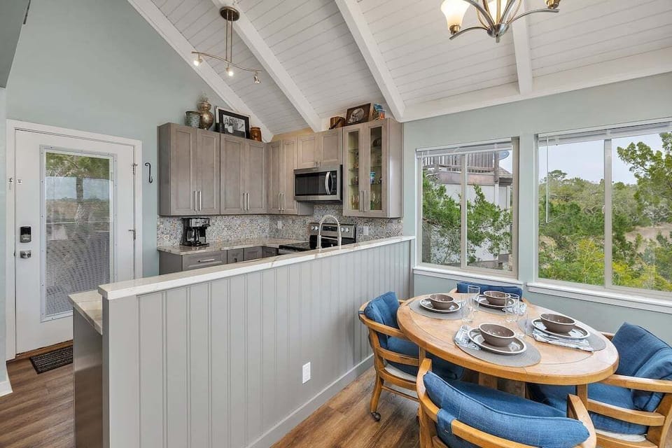 Dining area with round table, blue chairs, and kitchen beyond