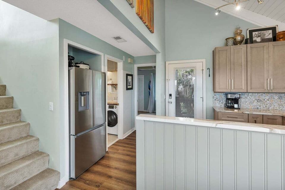Open interior with stainless refrigerator, stairs, and upper cabinets