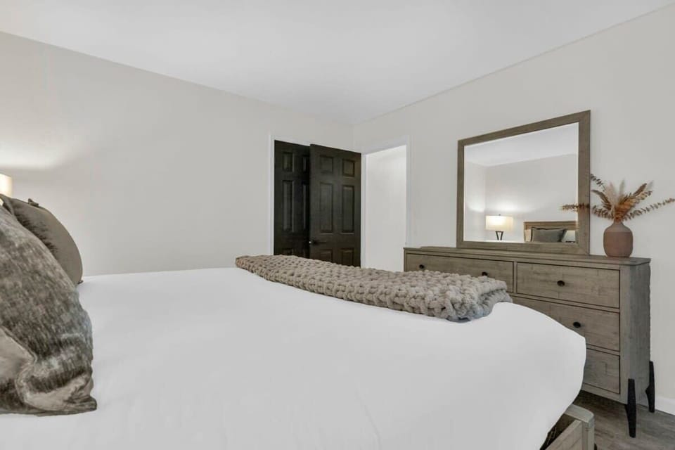 The second bedroom is a spacious room with a king-size bed, matching nightstands with lamps, and ample storage space with a dresser and closet.