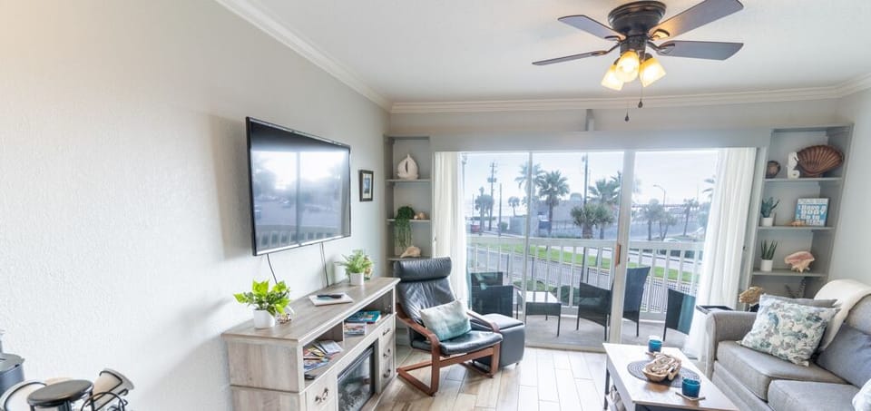 To the living room with comfy cozy furnishings, fireplace, TV and balcony access