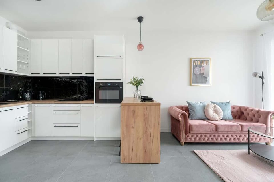 An open-plan kitchen and living area with a pink sofa and stylish décor, creating a cohesive and inviting space.

