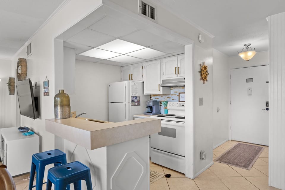 Step into your fully equipped kitchen with crisp white cabinets, modern appliances, and coastal nautical touches—perfect for preparing meals or morning coffee in your home away from home.