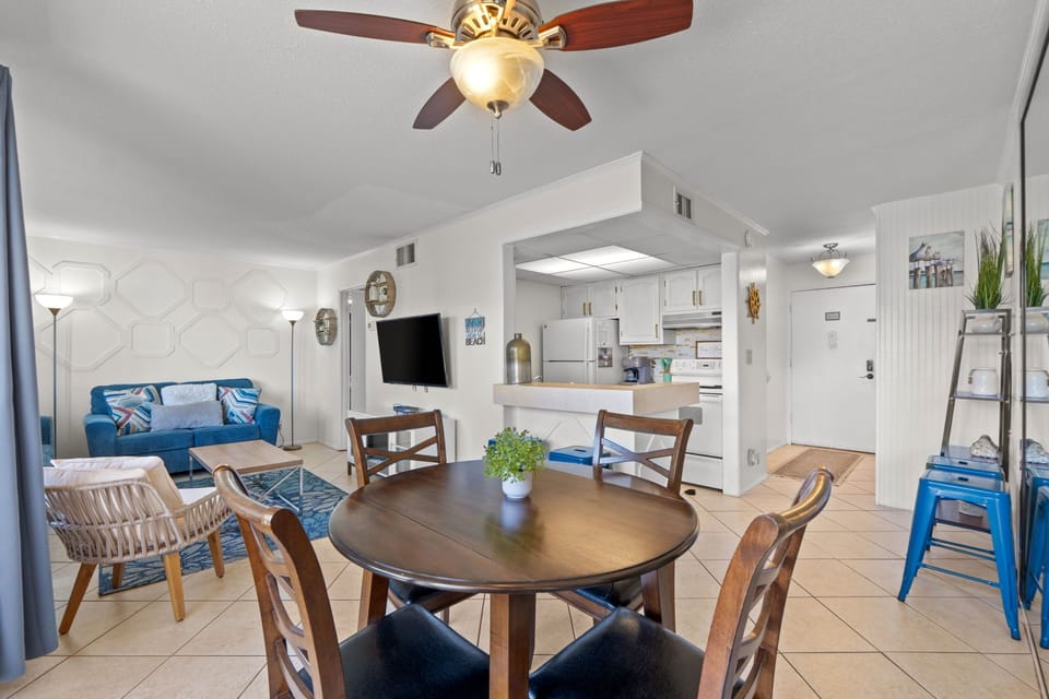 Relax in your open-concept living and dining space, perfect for gathering over meals or unwinding with coastal vibes. The ceiling fan keeps you cool while you enjoy your beachy retreat.