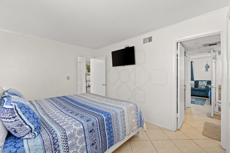 Your bedroom offers a cozy coastal vibe with soothing blue tones and all the comforts of home, including a wall-mounted TV for unwinding after a day of adventure.