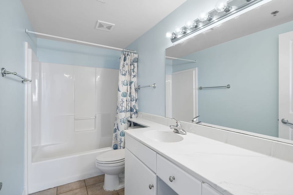 Clean bathroom with a large mirror and bathtub with shower curtain
