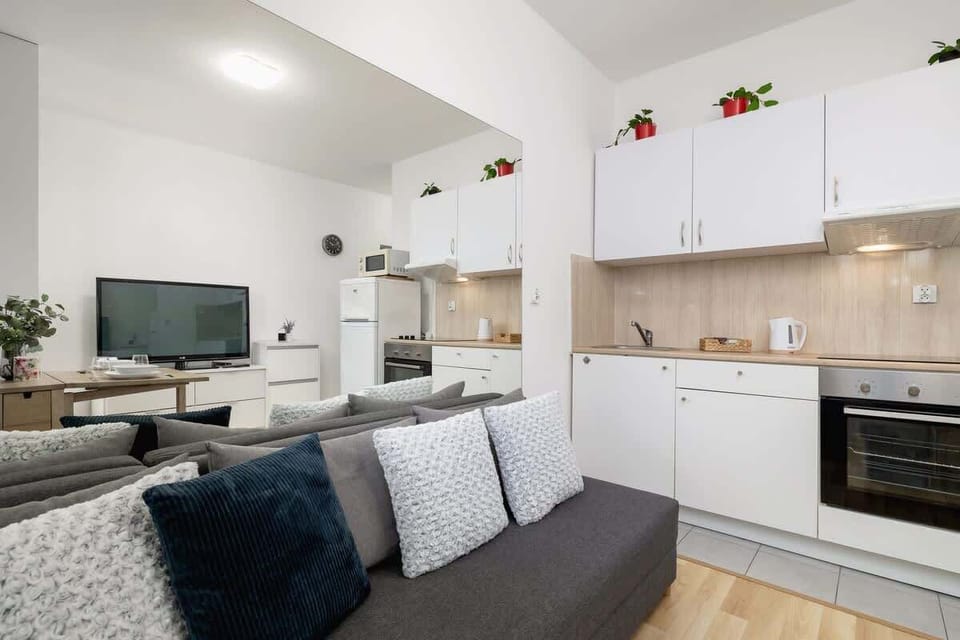 Spacious living area with a gray sofa, wooden coffee table, and modern TV setup, perfect for relaxation and entertainment.
