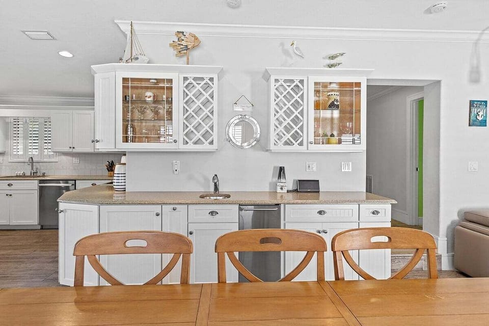 Gather around the farmhouse-style table beneath elegant lighting and relaxed island décor.