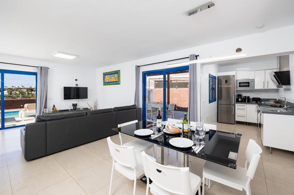Open-plan living room with sofa, dining area, kitchen, A/C, WiFi internet, and satellite TV