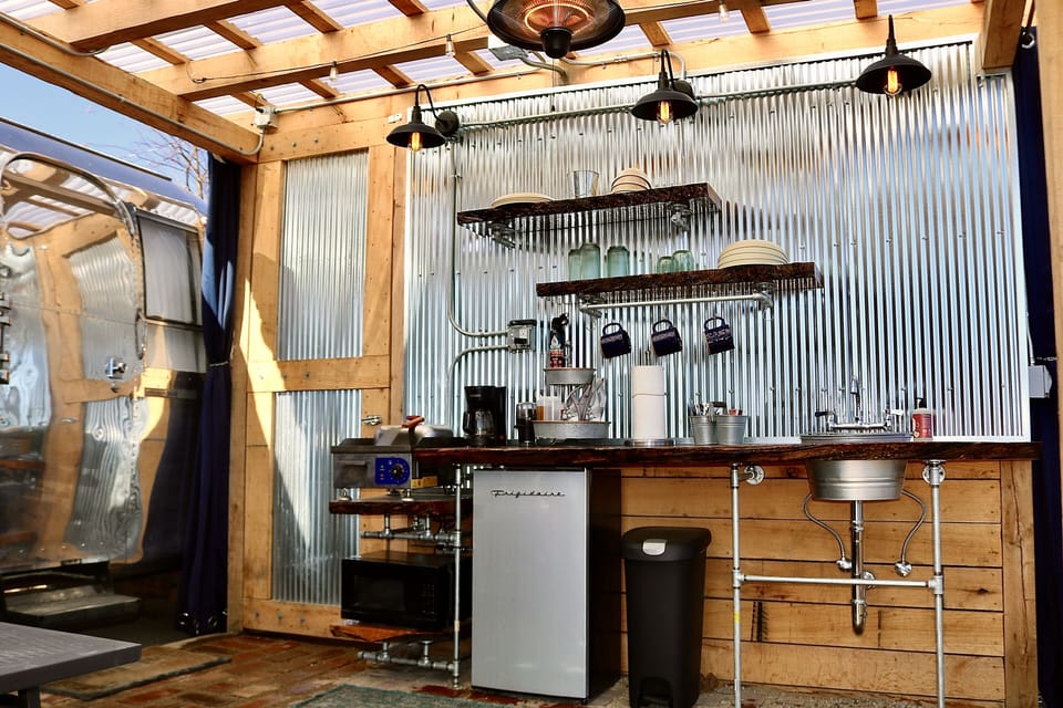 Outdoor kitchen with griddle, microwave, fridge & farm sink.