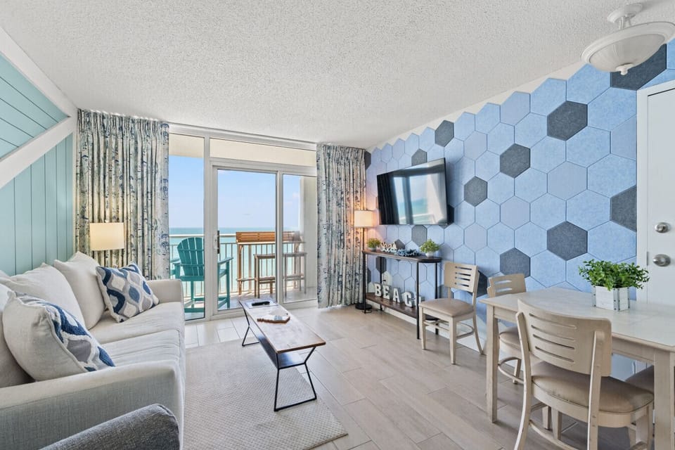 Oceanfront living room with Smart TV, sleeper sofa, and private balcony access. Sip coffee at the tiki bar while enjoying stunning ocean views at Camelot Resort Myrtle Beach.