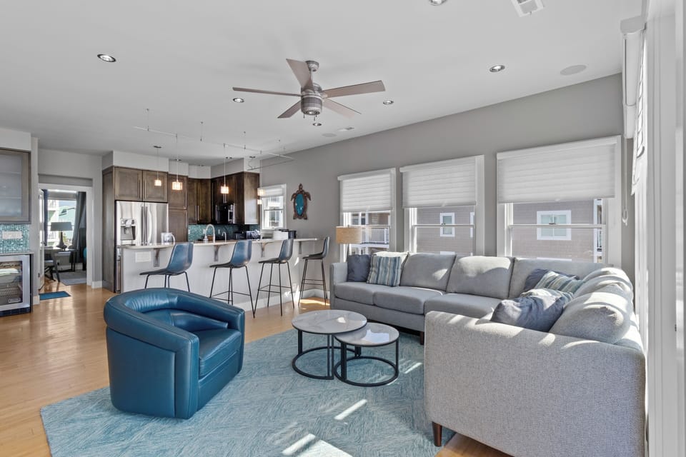Bright living room with ocean views, bamboo floors, high ceilings, and a 70” TV with surround sound.