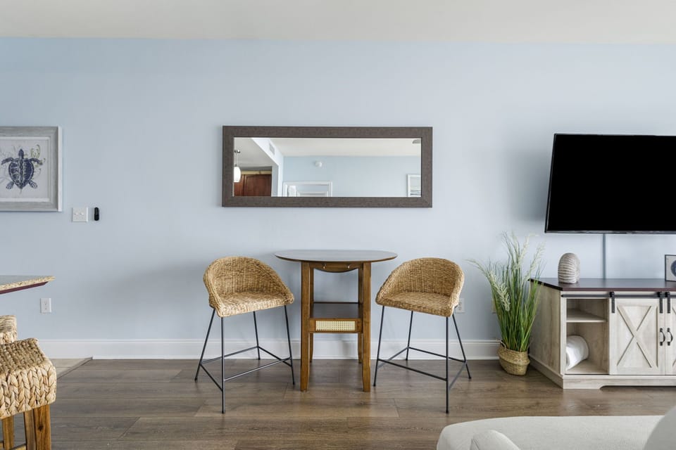 Cozy dining area with wicker chairs and a wall-mounted mirror in a modern living space