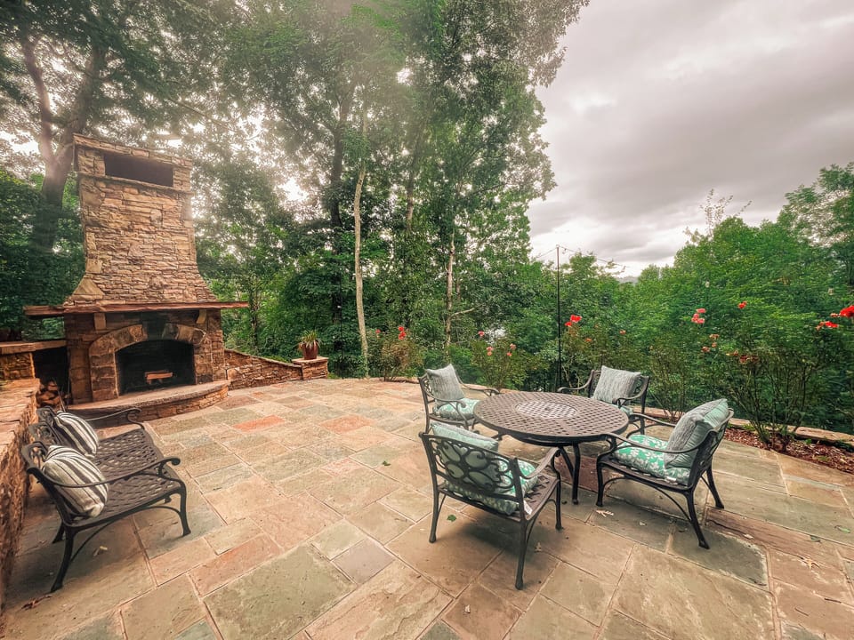 Summer view of private lower patio with large outdoor fireplace, lots of seating