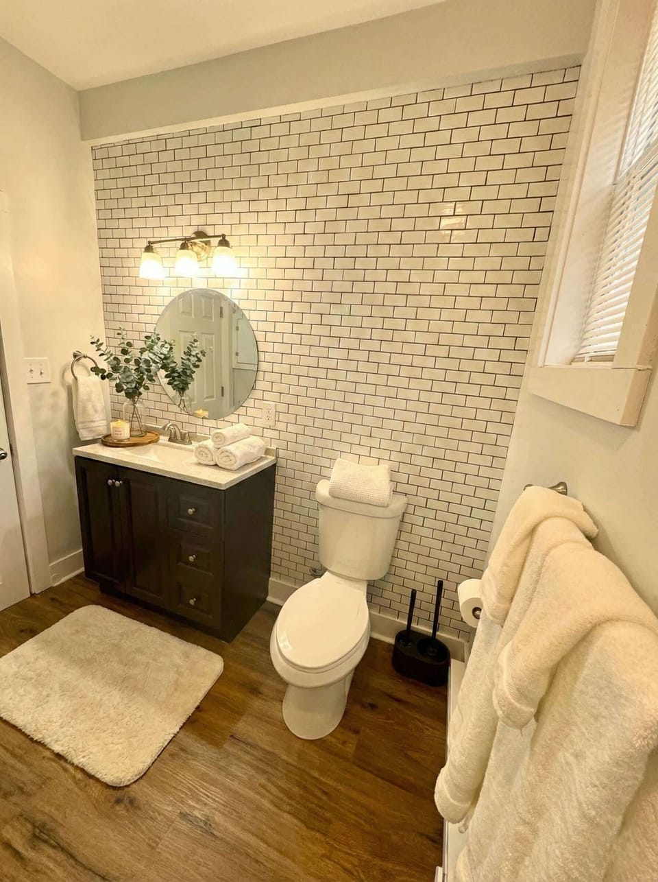 Bathroom with vanity, toilet, towels, and decorative tile accent wall.