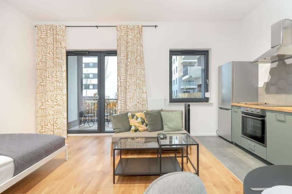 An open-plan kitchen and living area featuring modern appliances, a dining table, and a cozy lounge space.
