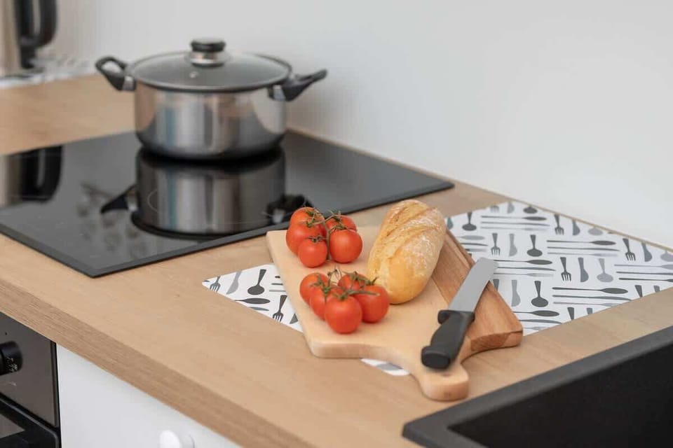 Kitchen countertop with a pot on the stove and fresh vegetables, illustrating a functional cooking space.
