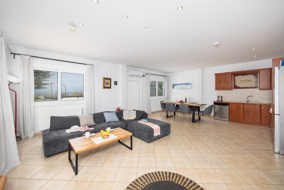 Open-plan living room with sofa, dining area, kitchen, ornamental fireplace, A/C, WiFi internet, and satellite TV