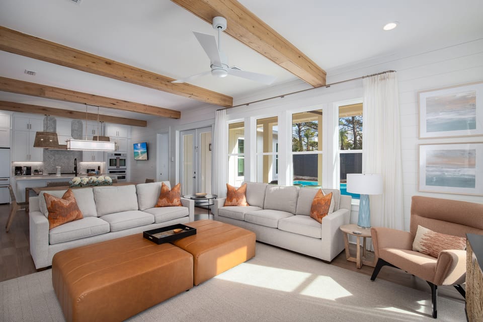 Settle into your spacious living area where warm wood beams frame comfortable seating and pool views invite relaxation.