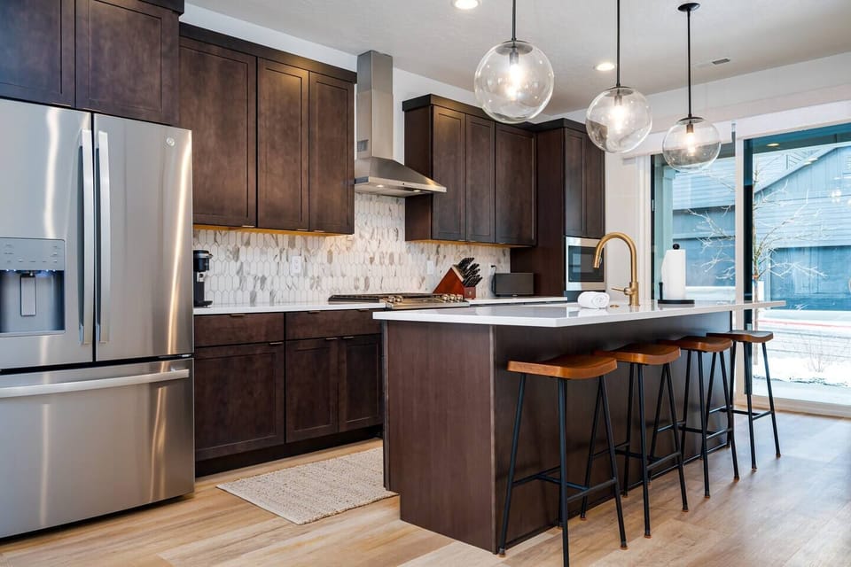 The gourmet kitchen features an island with seating for four and is equipped with brand-new stainless steel appliances, including a microwave, gas stove, and spacious refrigerator.