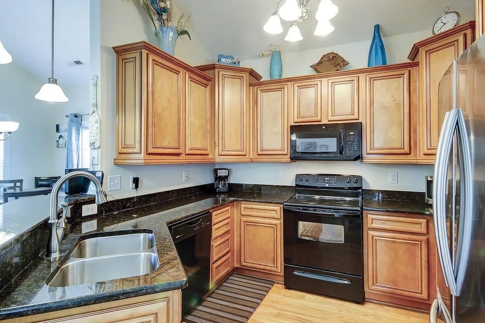 Sleek kitchen with granite counters, wood cabinetry, and modern appliances.