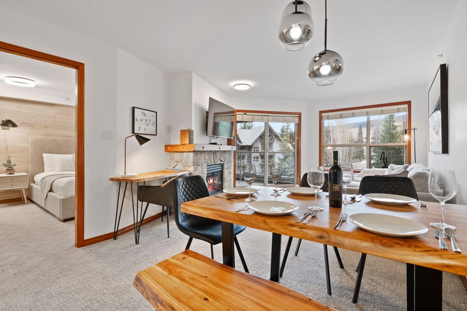 Open concept living room with a dedicated workspace, stunning solid wood dining table and mountain views.