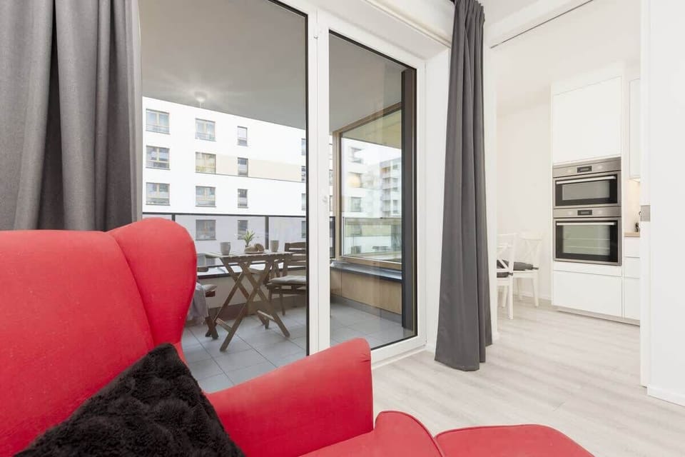A balcony with outdoor seating overlooking a modern residential complex, perfect for relaxing with a view.
