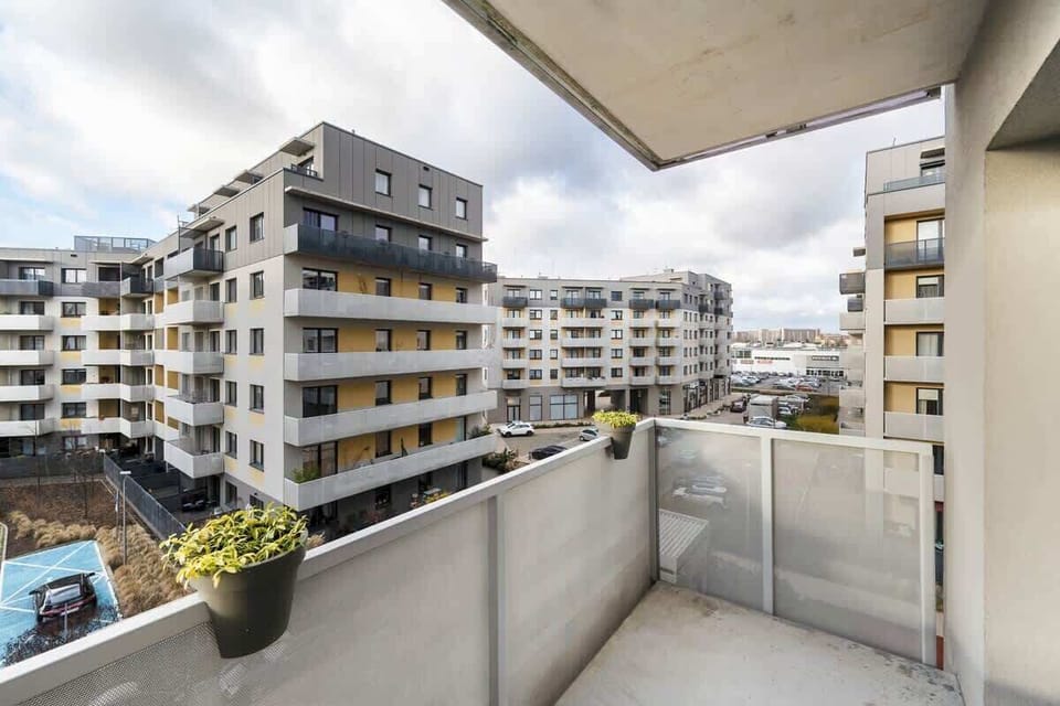 A balcony with grey tiles and a view of a modern residential complex with multi-level balconies.
