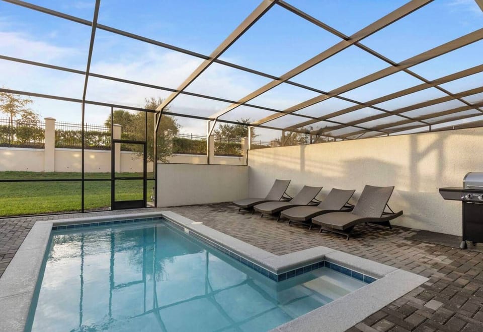 Step into a sunlit oasis featuring a private pool surrounded by sleek lounge chairs and a spacious patio. The modern design and expansive glass enclosure create a refreshing atmosphere, perfect for relaxing or entertaining.