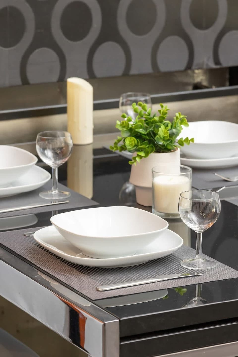 A close-up of a beautifully set dining table with elegant plates, candles, and sophisticated tableware.
