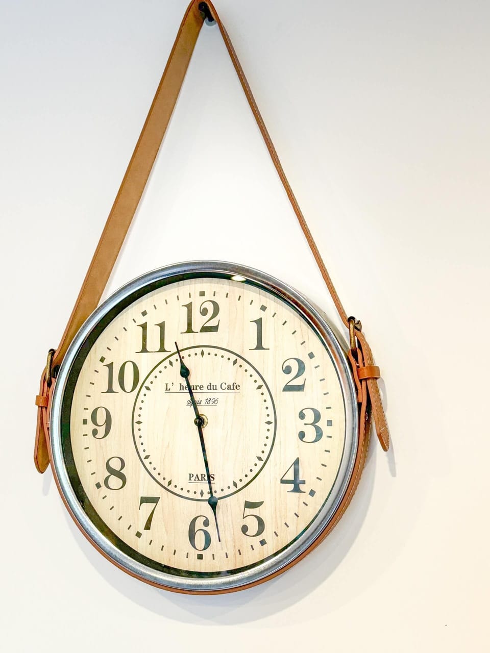 A vintage-style wall clock with Roman numerals and a leather strap, adding a charming and rustic detail to the decor.
