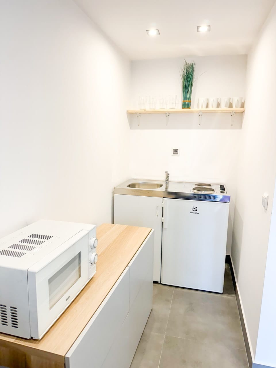 A small laundry room with a washing machine, dryer, and practical shelving, offering a functional and organized utility area.
