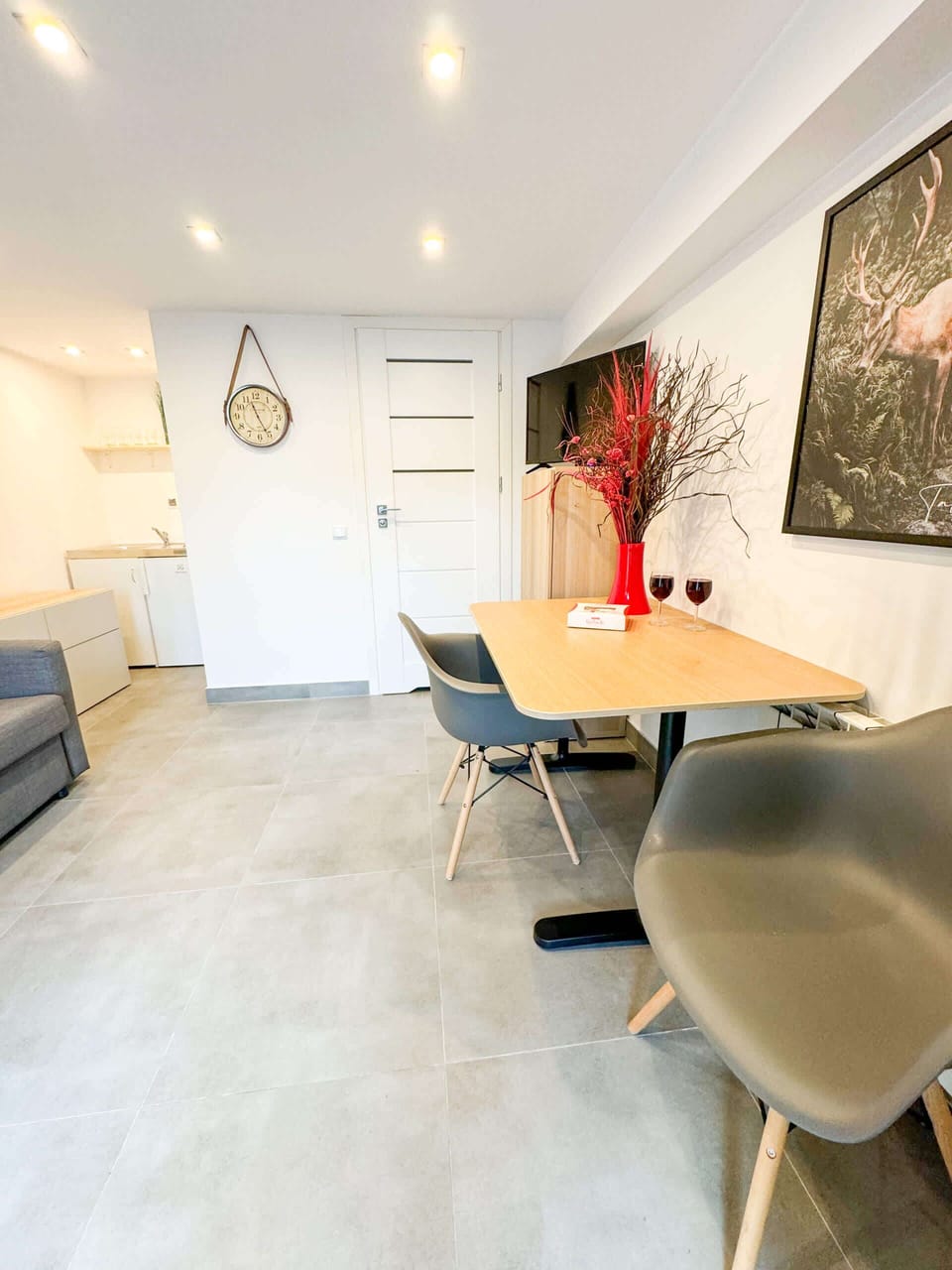 An open-concept living and dining area with a modern table, grey chairs, and vibrant red decor, creating a dynamic and elegant space.
