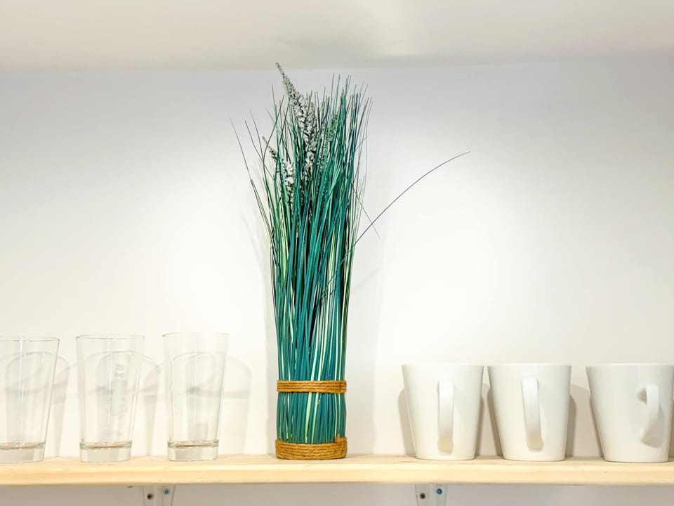 A decorative arrangement with tall green reeds in a turquoise vase, adding a fresh and vibrant touch to the room.
