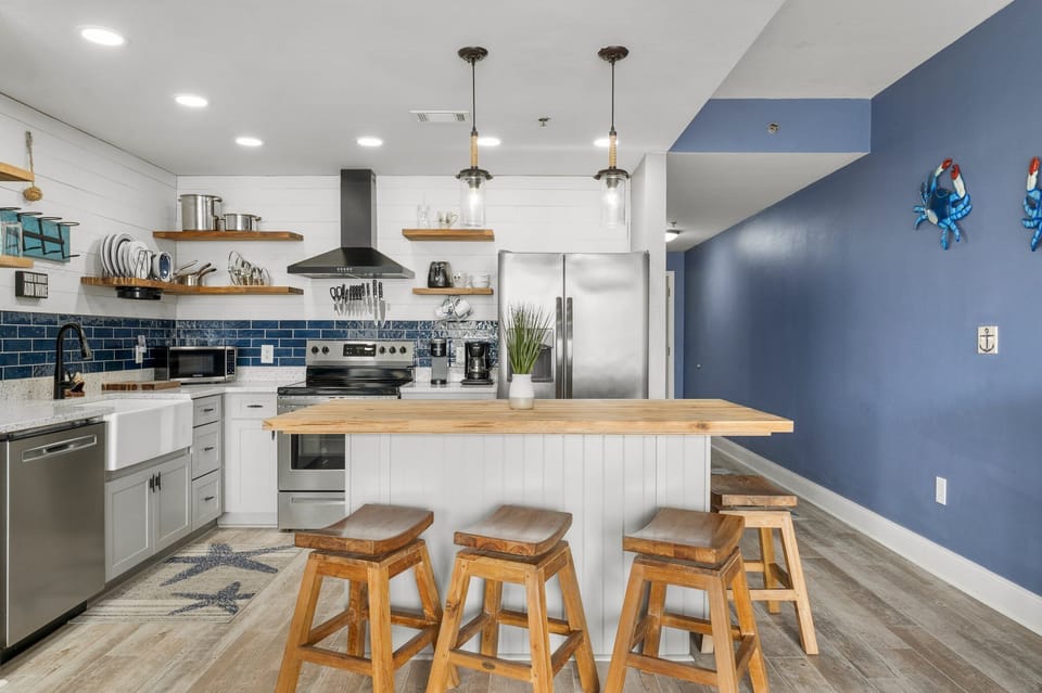Modern kitchen with a wooden island and blue accent wall for a coastal-inspired atmosphere.
