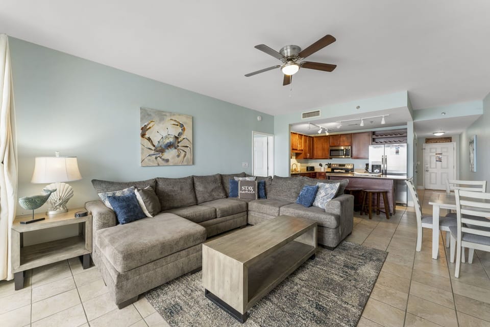 Spacious living area with a large sectional sofa and open kitchen in a modern coastal style.