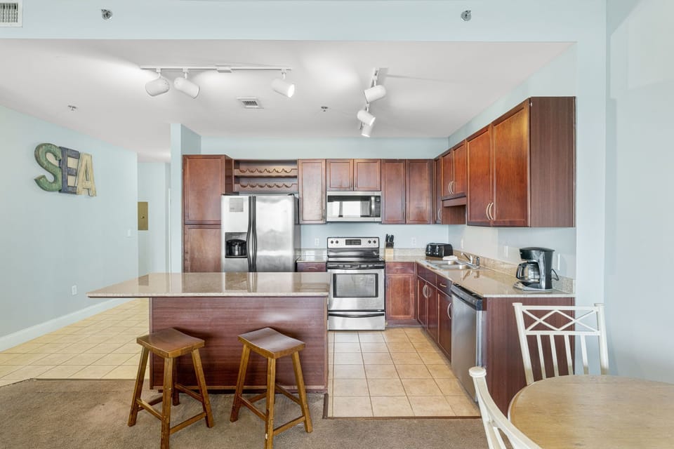 Modern kitchen with stainless steel appliances and a breakfast bar with seating.