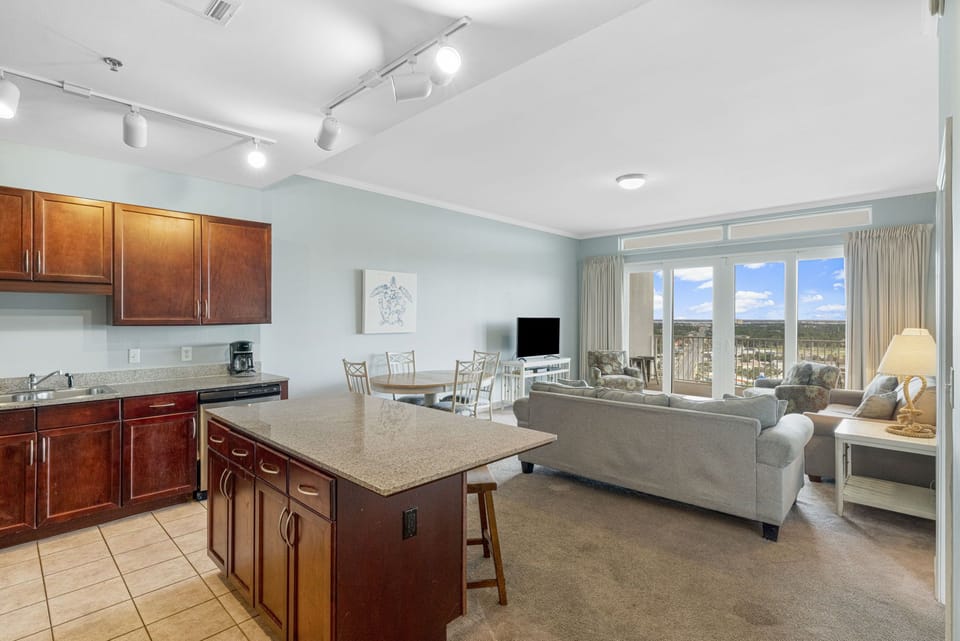 Open-concept living area with kitchen island and large windows offering city views