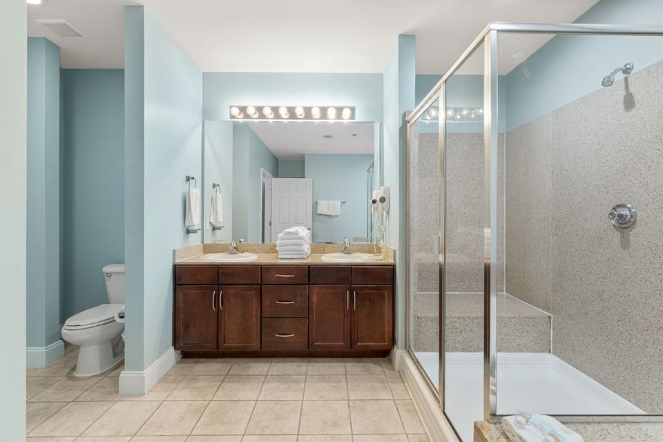 Spacious bathroom with dual sinks and a glass-enclosed shower in a modern setting.