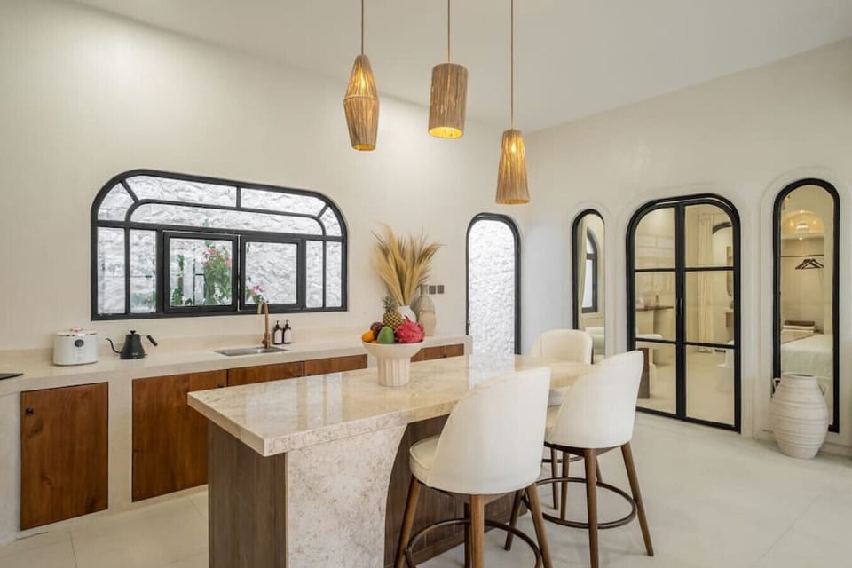 Spacious and inviting dining area in a modern kitchen, highlighted by natural light streaming through a distinctive arched window, with stylish bar stools providing a cozy spot for casual meals.