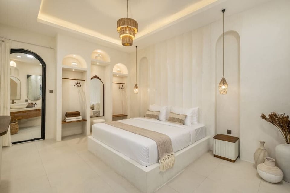 an elegant bedroom with Mediterranean-inspired design, featuring white furniture and arched doorways for a serene atmosphere.