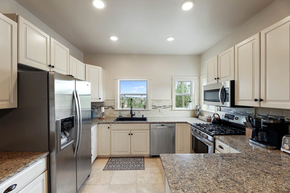 Thoughtfully equipped kitchen with large island, coffee station, and forest-facing windows