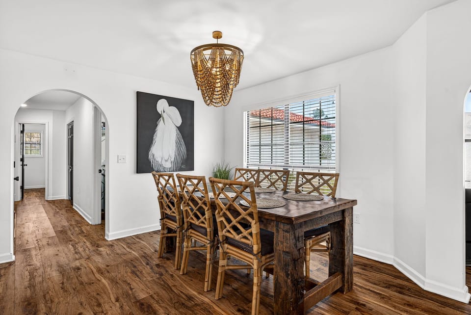 Gather around the rustic dining table beneath a stunning chandelier for meals, laughter, and shared moments in your coastal-chic home away from home.