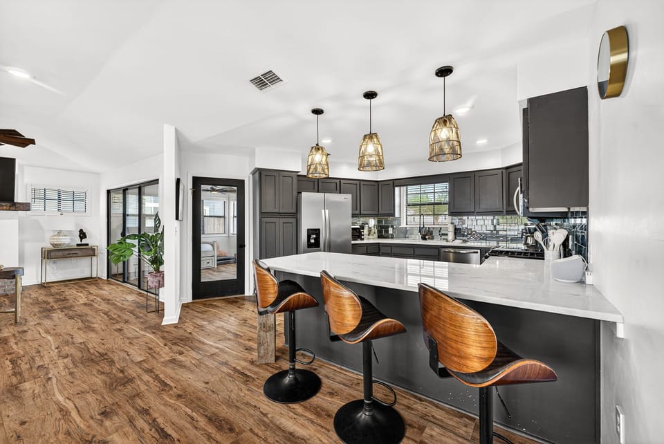Step into your chef's dream: a modern kitchen with marble countertops, chic pendant lights, and a spacious island inviting you to gather and create unforgettable meals together.